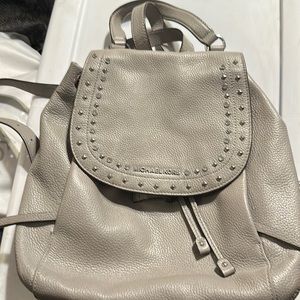 Michael Kors gray backpack with silver detail on the flap